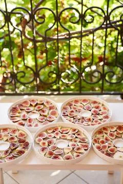 Figs drying process on plates on the table on the balcony Stock Photos