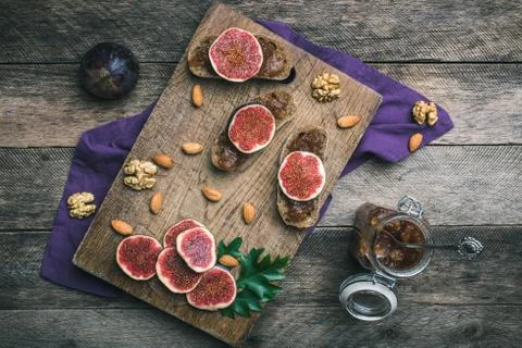Figs, nuts and bread with jam on choppingboard in rustic style Stock Photos