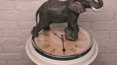 Figure of elephant standing on a rotating clock Stock Footage 56813363