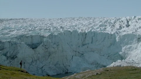 Figure looking at huge Glacier Stock Footage 74870258