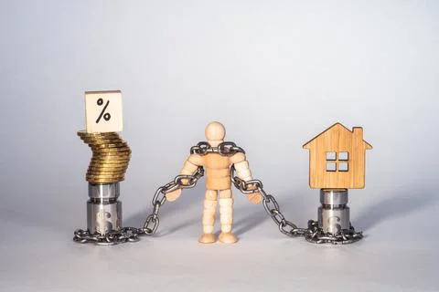 Figure of a man made of wood in chains tied to metal weights with the symbol of Stock Photos