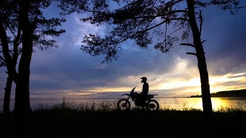 Figure of man on motorbike posing on background of sunset Stock Footage