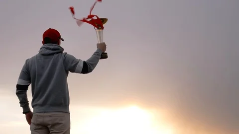 The figure of man with trophy winner cup on the clouds background Stock Footage 87195140