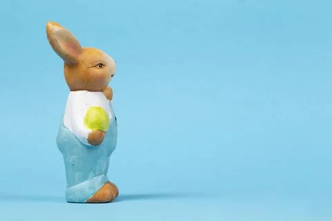 Figure of a teddy Easter bunny with an egg on a blue background. Easter card. Foto stock