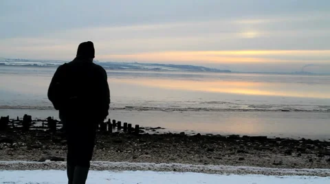 Figure walking towards winter ocean Stock Footage 1049724