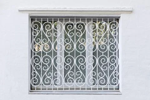 Figured frame of the window with iron forged white grating Stock-Fotos