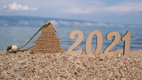 Figures 2021 and a Christmas tree decoration stand on the sand by the beach. Stock Footage 144375615