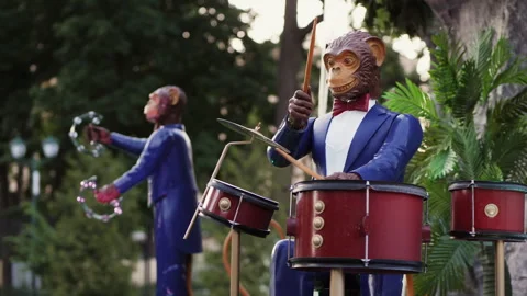 Figures of monkeys in blue suits playing musical instruments on the street Stock Footage 277401172