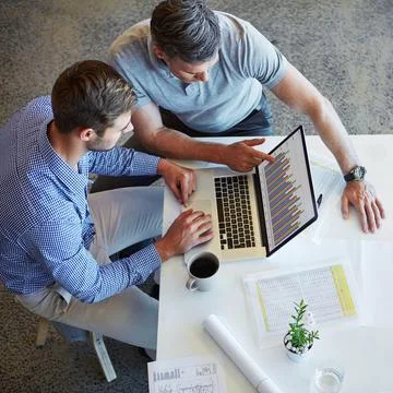 The figures show exponential growth. two colleagues using a laptop in a meeting Stock Photos