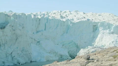 Figures walk to the huge Glacier Stock Footage 74870962