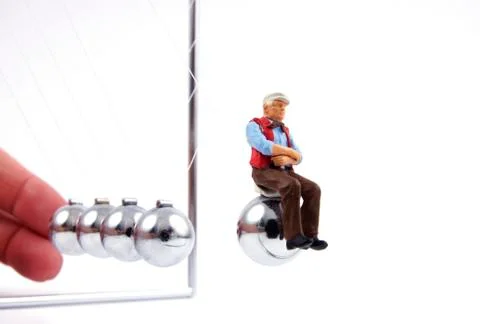 Figurine of old man ejected by newton's cradle, close up Stock Photos