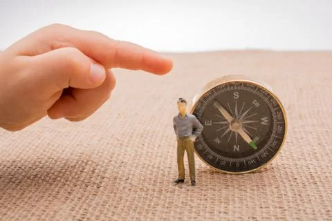 Figurine by the side of a compass Stock Photos