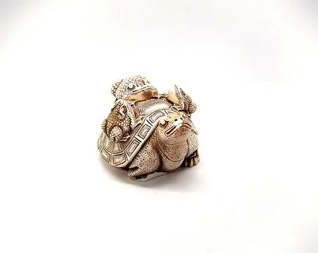 Figurine of a turtle with three frogs on a shell on a white background. 写真素材