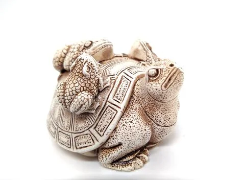 Figurine of a turtle with three frogs on a shell on a white background. Stock Photos