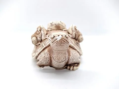 Figurine of a turtle with three frogs on a shell on a white background. Stock Photos