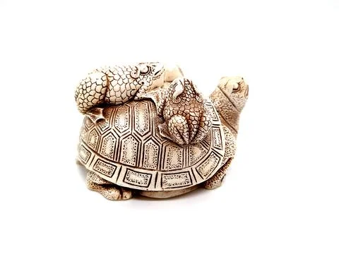 Figurine of a turtle with three frogs on a shell on a white background. Stock Photos