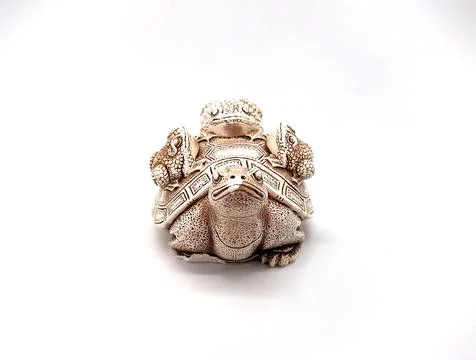 Figurine of a turtle with three frogs on a shell on a white background. Foto stock