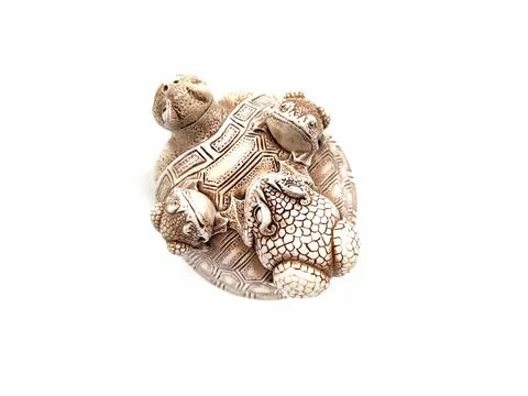 Figurine of a turtle with three frogs on a shell on a white background. Stock Photos