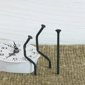 Figurines of man made from carpentry nails. They are sitting on the watch dia Stock Photos