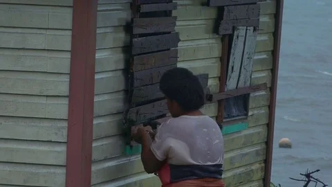 Fijian woman boarding up her house during a Tropical Cyclone Stock Footage