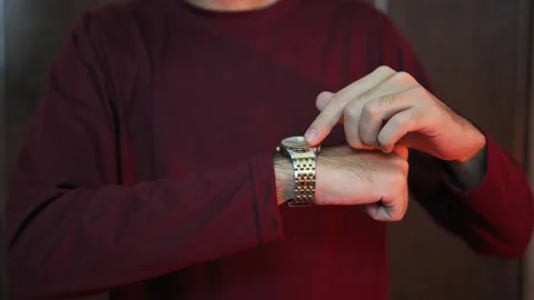File #  1757471404A man sits on a sofa and looks at his wristwatch. The man 库存影片 337847460