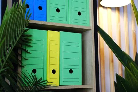 File folders for storing documents are on a wooden shelf in the office. Stock Photos