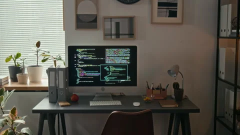 File Rack and Work Desk with Computer Monitor Displaying Software Code in Office Stock Footage 329609587