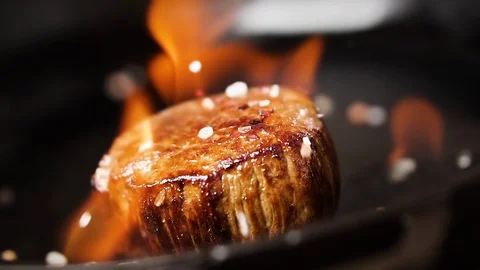 Filet mignon steak is fried in a pan with fire. Salt falls on a steak. 動画素材 126006786