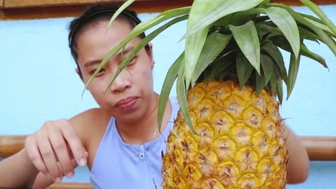 The Filipina puts her head on the table and looks at the pineapple. Video stock 137943544