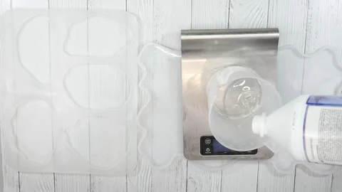 Fill a container with Resin Epoxy on a scale, black gloves hand take the bott Video stock 146238338