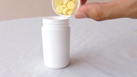 Fill up a tiny white jar with a bunch of vitamin C pill Stock Footage 145562470