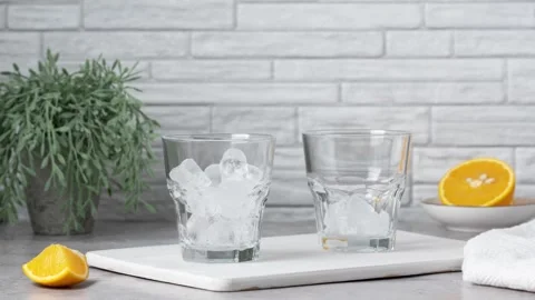 Fill two glasses with ice and add orange juice. Stop motion animation Stock Footage 340459933