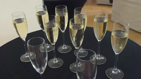 Filled and empty champagne flutes on a round black table indoors Stockbeeldmateriaal 341830233