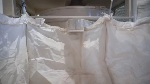Filling big plastic bag with dry dust like material in workshop Stock-Footage 304396042