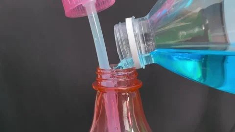 Filling up blue liquid hand sanitiser to pink foggy sprayer bottle close up view Stock Footage 250087772