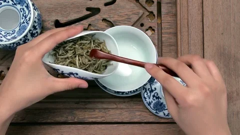 Filling a brown teapot through a funnel. Porcelain chinese cups, steel teaspoon Stock Footage