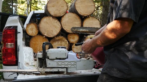 Filling chain saw with gasoline with firewood in the background Stock Footage 117825341
