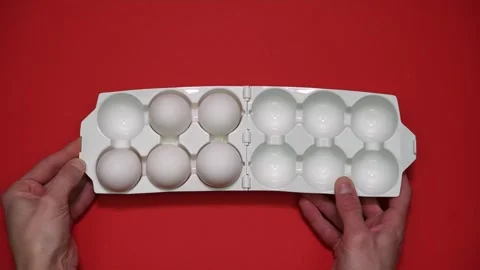 Filling a chicken egg tray with eggs on a red background. Full tray of eggs Vídeos de archivo 297398149