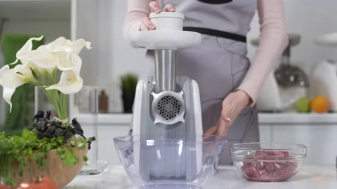 Filling comes out through raw meat grinder sieve. Electric mincer machine with Stock Footage 130193767