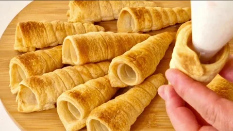 Filling crispy puff pastry cream horns with white whipped cream using piping bag Stock Footage 327259717