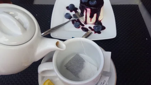 Filling a cup with hot water, tea bag to drink tea with blueberry cheese dessert Stock Footage 69932285