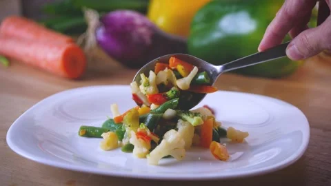Filling up a dish of cooked vegetable. A spoon of mixture of carrots, broccoli,  Stock Footage 144260778