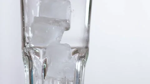 Filling elegant glass with large ice cubes to prepare drink Stockbeeldmateriaal 153070372