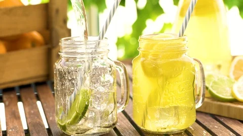 Filling fresh lemonade in mason jar glass on wooden table outside Stock Footage 93783611