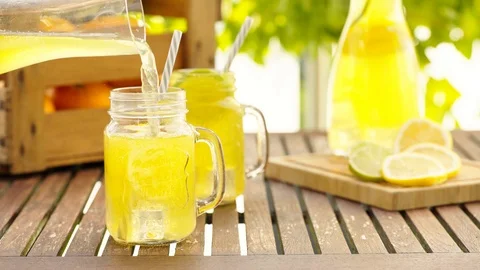 Filling fresh lemonade in mason jar glass on wooden table outside Stock Footage 93783725