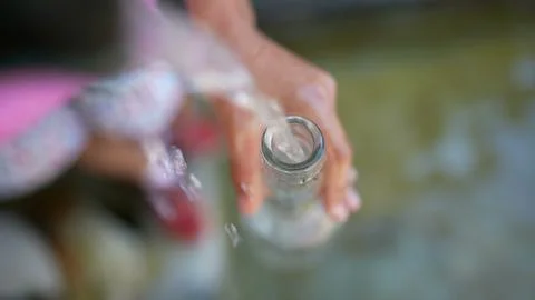 Filling glass bottle water from faucet during summer day Stock Photos