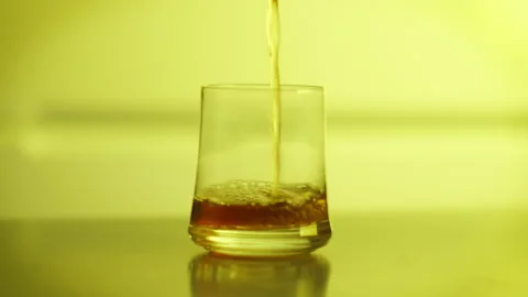 Filling a glass with a drink, close-up, colored background Stock Footage 148336014