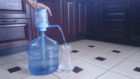 Filling a glass jug with drinking water from a 19 liter plastic bottle Stock Footage 182556182