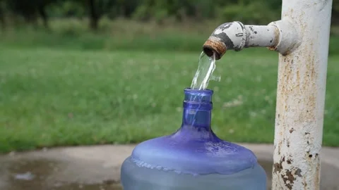Filling a large blue water bottle from an outdoor tap Stock Footage 340834872