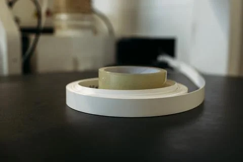 Filling the machine with a PVC edge for edging parts made of chipboard. Stock Photos